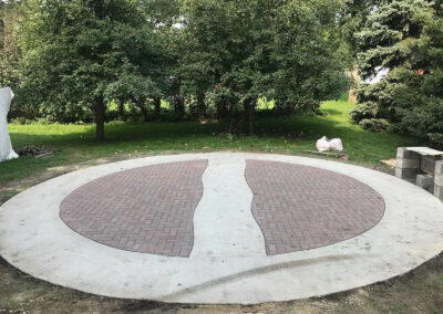 Circular decorative patio with brown pavers and concrete trimming.